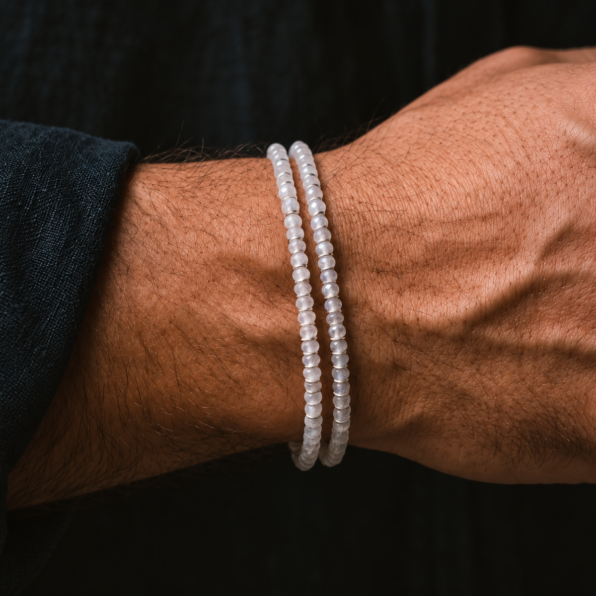 Moonstone Bracelet X (4mm), shown in a two-row wrist stack beside a dark sleeve.