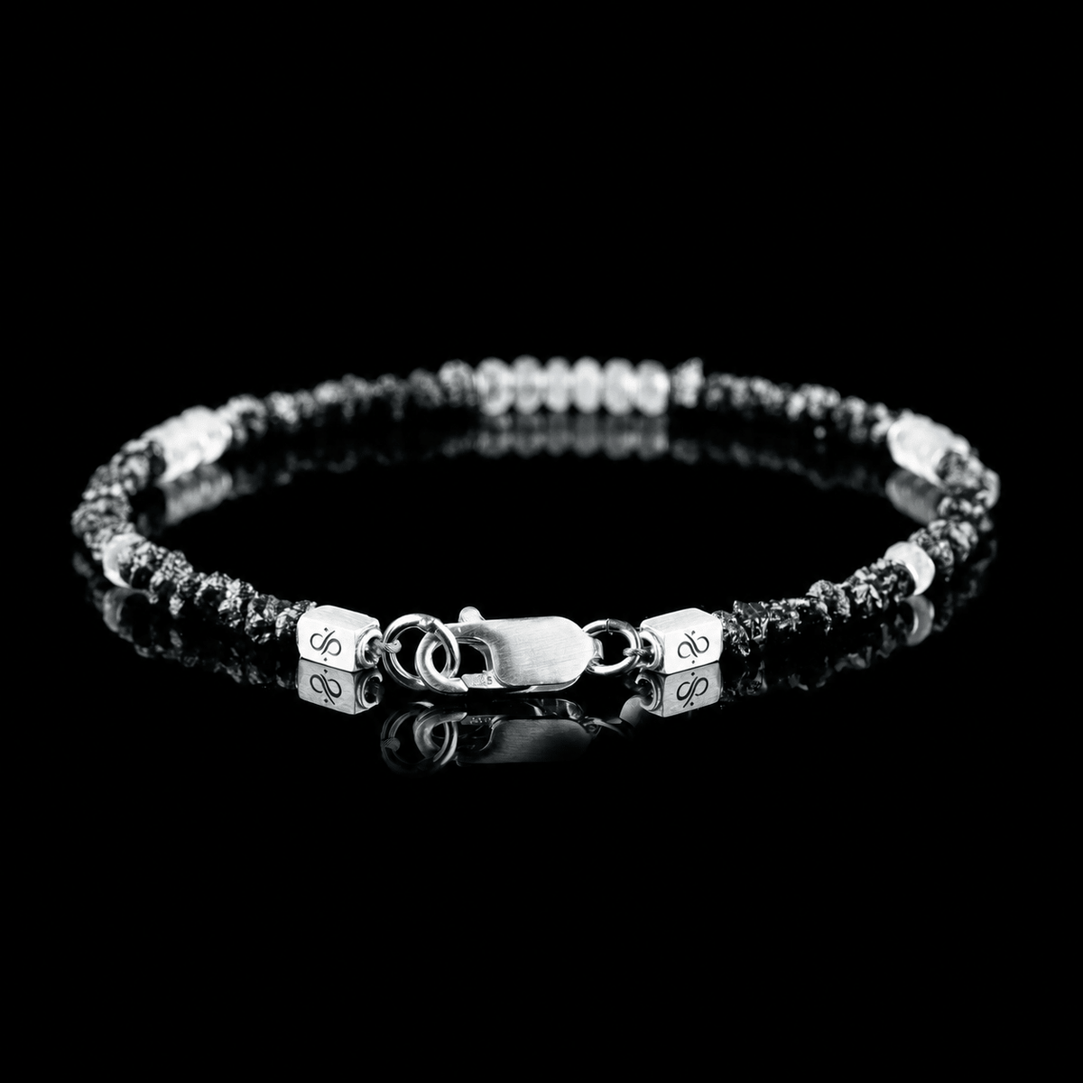 Back view of Raw Black Diamond - Moonstone Bracelet I (3-4mm), showing the clasp and branded end pieces on a black reflective surface.