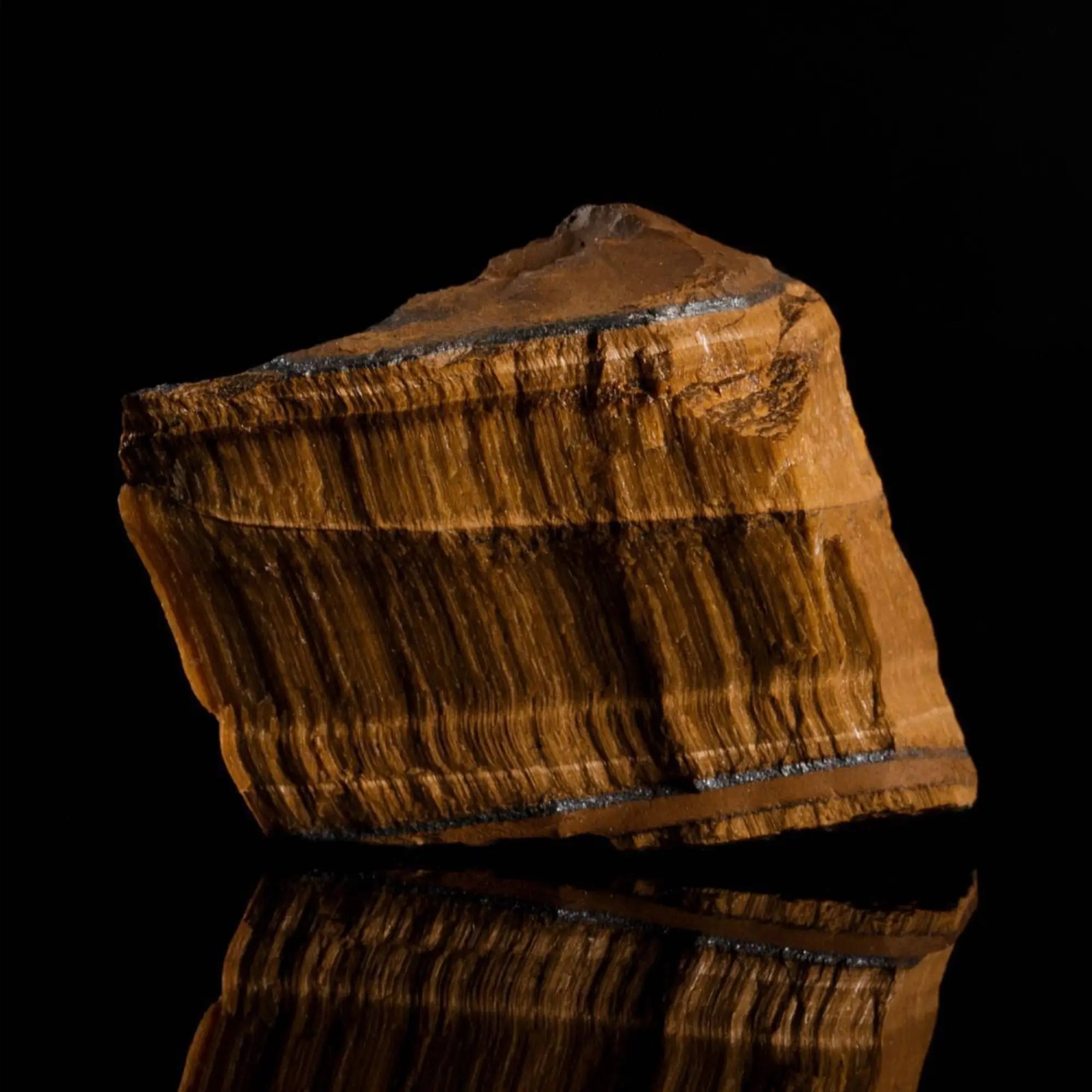Raw, uncut tiger eye stone showing the natural mineral source. Aurum Brothers.
