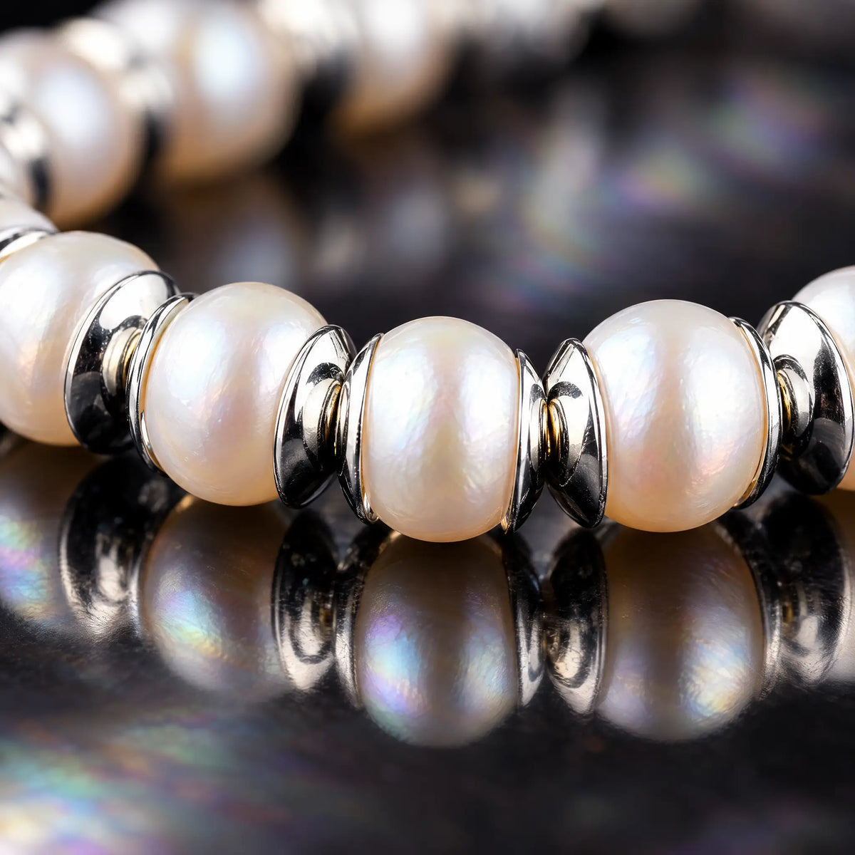 Macro detail of White Pearl Bracelet II (6.5mm), showing the pearls' lustre and silver spacers on a reflective surface.