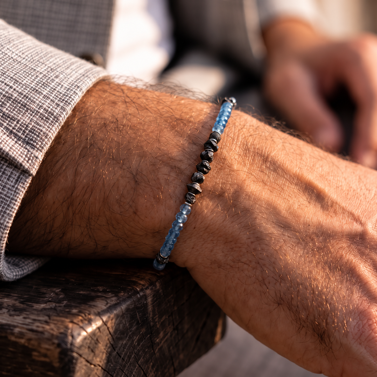 Raw Black Diamond - Aquamarine Bracelet I (4mm), showing blue aquamarine and a rough black diamond centre on a wrist beside a grey jacket.