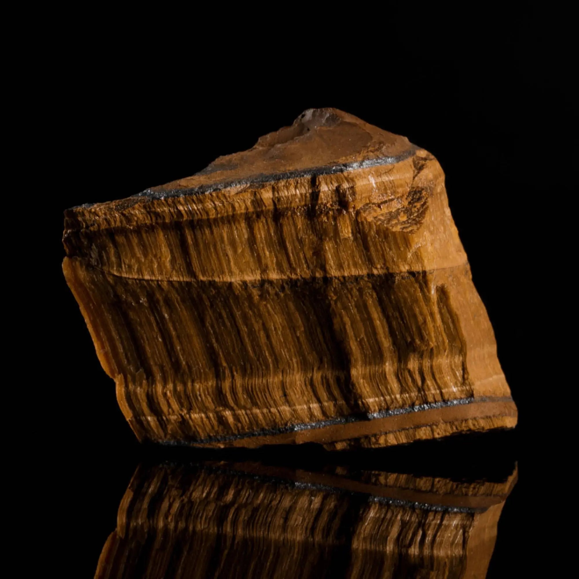 Raw, uncut tiger eye stone showing the natural mineral source. Aurum Brothers.